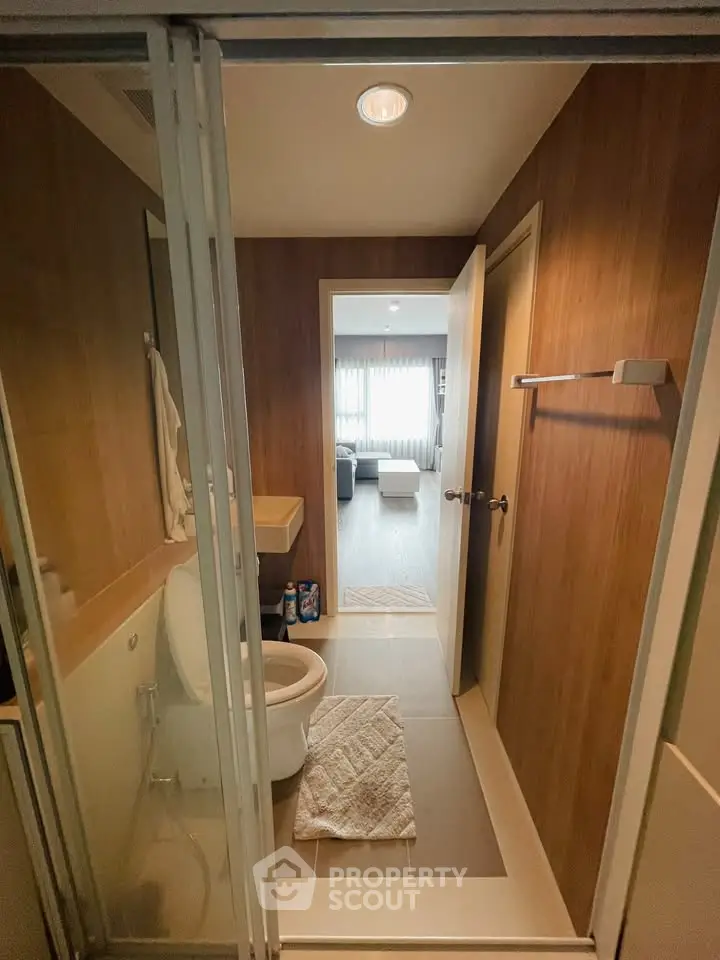 Modern bathroom with wooden accents and view into a cozy living room