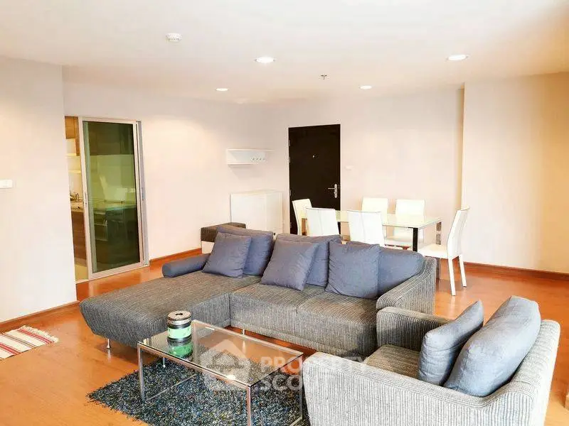 Spacious modern living room with stylish gray sofa and dining area, perfect for entertaining.