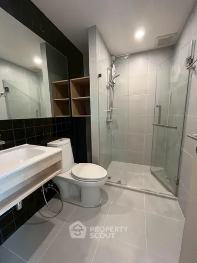Modern bathroom with glass shower and sleek fixtures in contemporary apartment.