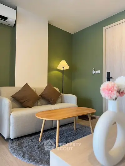 Charming living room with cozy sofa, stylish lamp, and modern decor in a serene green setting.