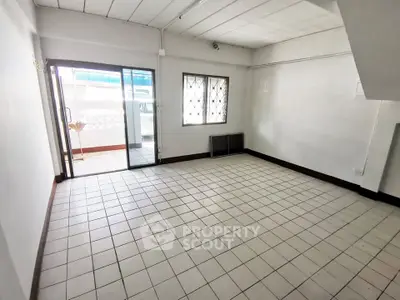 Spacious tiled room with balcony access and natural light, ideal for versatile living space.