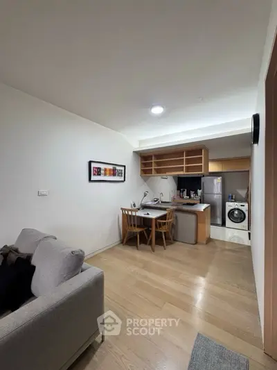 Modern open-plan living room with kitchen and dining area, featuring sleek appliances and cozy furnishings.