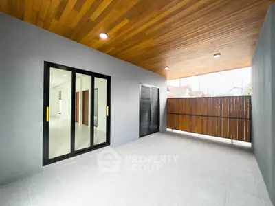 Spacious modern balcony with wooden ceiling and sliding glass doors, perfect for relaxation.