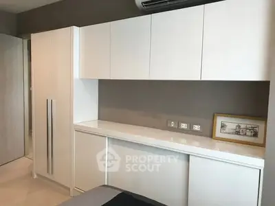 Modern bedroom with sleek white cabinetry and air conditioning unit