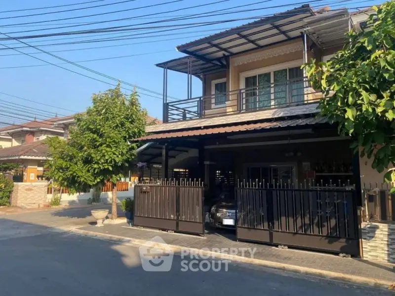 Charming two-story house with gated driveway and lush greenery in a serene neighborhood.