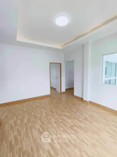 Spacious empty room with wooden flooring and modern ceiling light, perfect for customization.