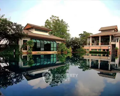 Luxurious waterfront villa with lush greenery and reflective pool, boasting serene views and modern architecture for an exclusive living experience.