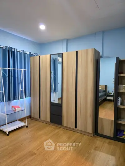 Spacious bedroom with modern wardrobe and wooden flooring