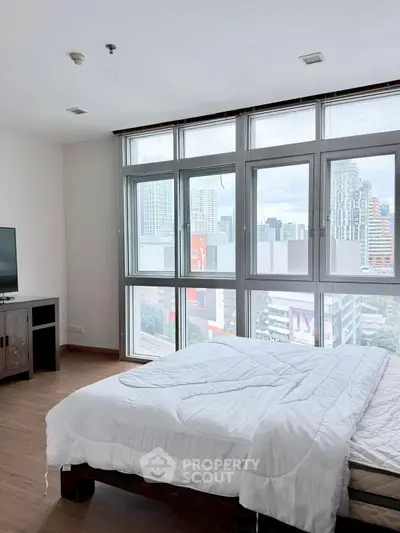 Spacious bedroom with city view and large windows in modern apartment