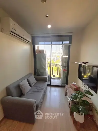 Cozy living room with balcony view, featuring a comfortable sofa and modern decor.
