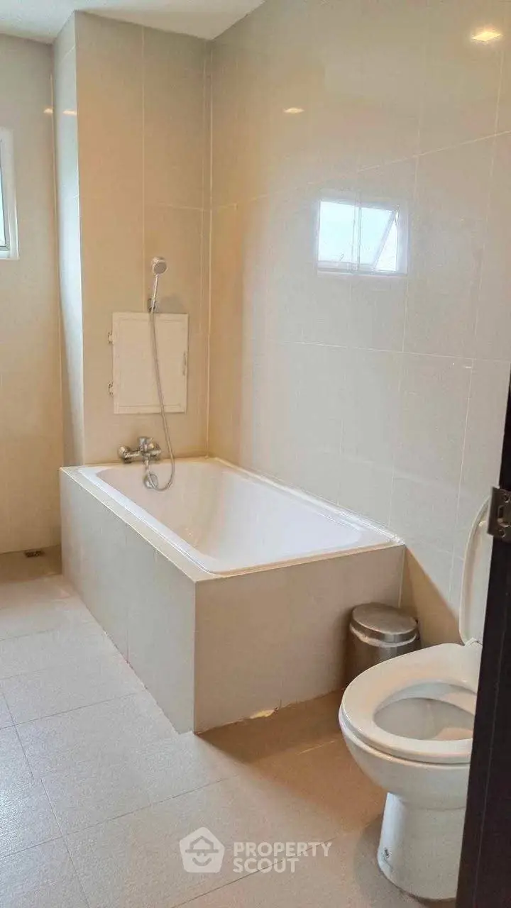 Modern bathroom with bathtub and toilet in a sleek design.