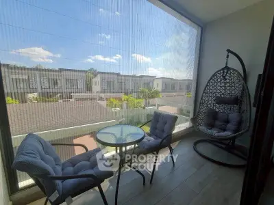 Charming balcony with cozy seating and scenic view of modern townhouses, perfect for relaxation.