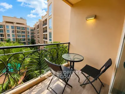 Charming balcony with cozy seating and lush garden view in modern apartment complex.