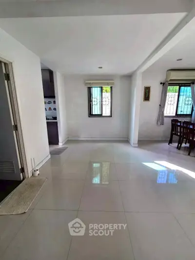 Spacious open-plan living area with large windows and tiled flooring, perfect for modern living.