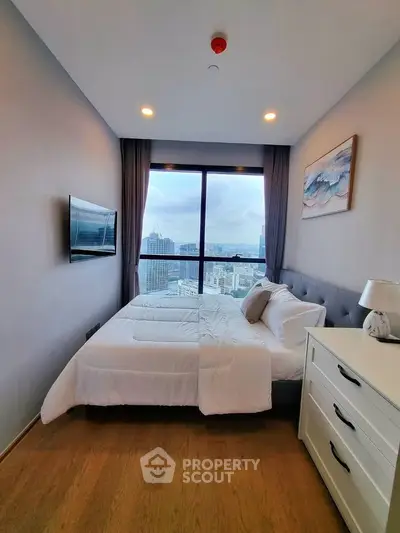 Modern bedroom with city view, featuring a cozy bed, wall-mounted TV, and elegant decor.
