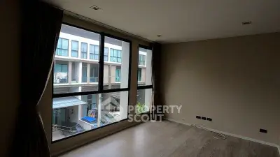 Spacious room with large windows offering a view of modern buildings, ideal for natural light.