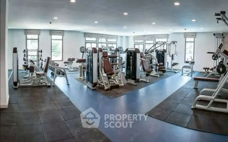 Spacious modern gym with state-of-the-art fitness equipment and large windows for natural light.