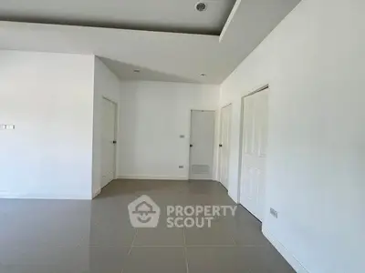 Spacious empty room with modern white doors and glossy tiled floor, ideal for customization.