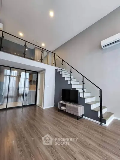 Modern duplex living room with sleek staircase and glass partition