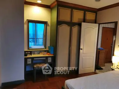 Cozy bedroom with built-in wardrobe and vanity, featuring warm lighting and elegant wood flooring.