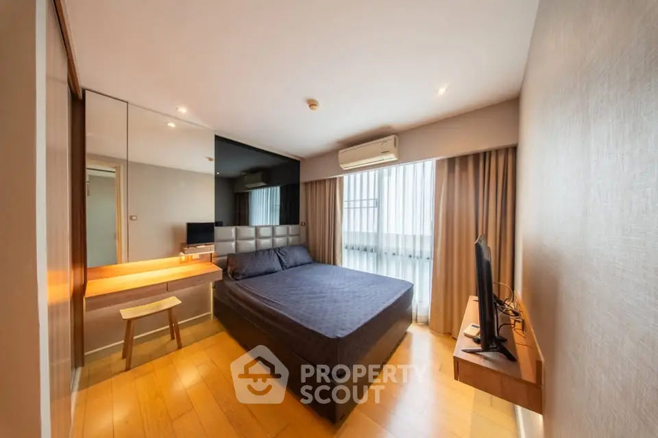 Modern bedroom with sleek design, featuring a comfortable bed, wooden flooring, and ample natural light.