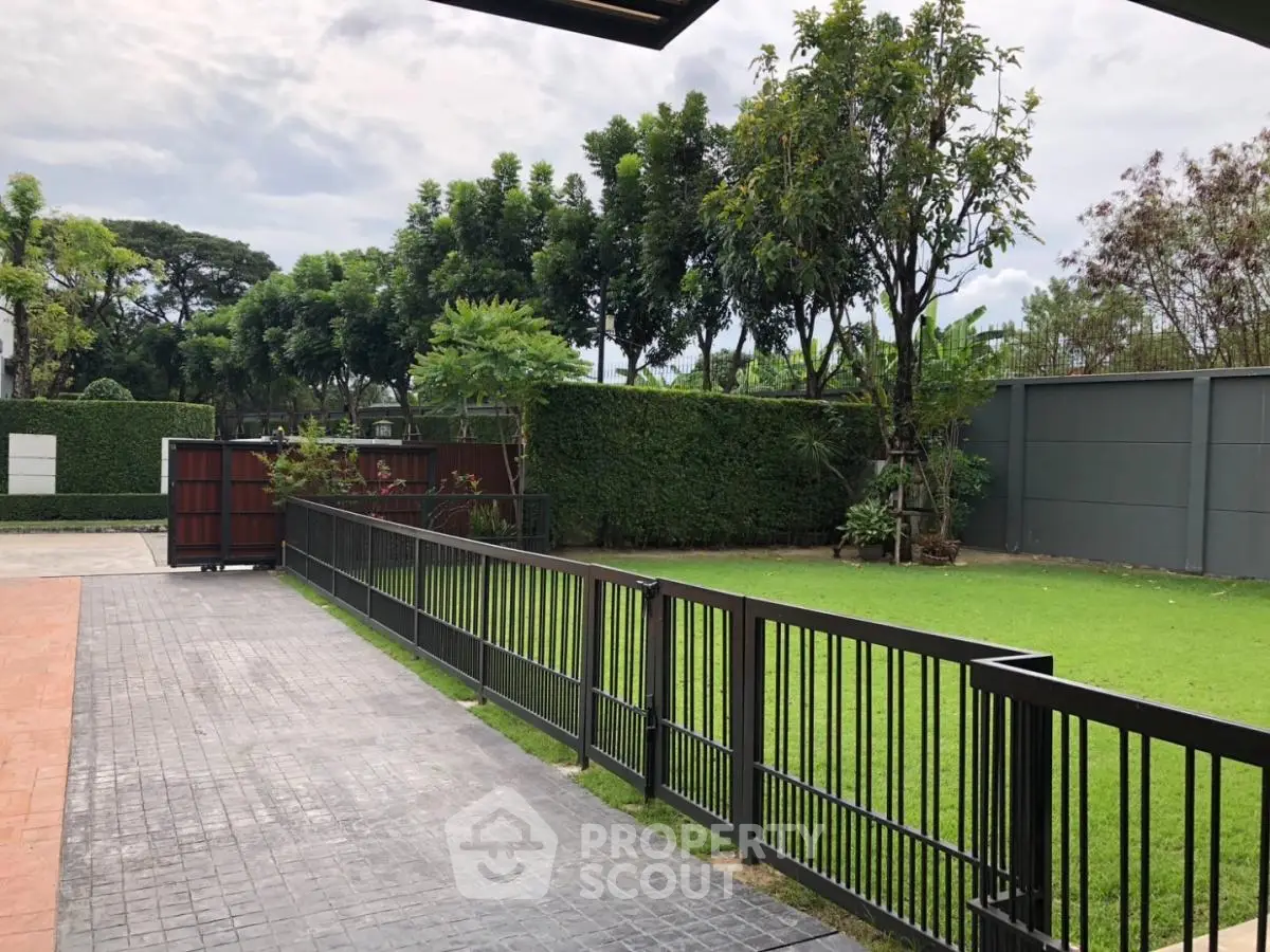 Spacious garden with lush greenery and modern fencing in a serene residential area.
