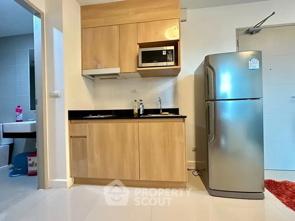 Modern kitchen with sleek cabinetry and stainless steel fridge in compact apartment