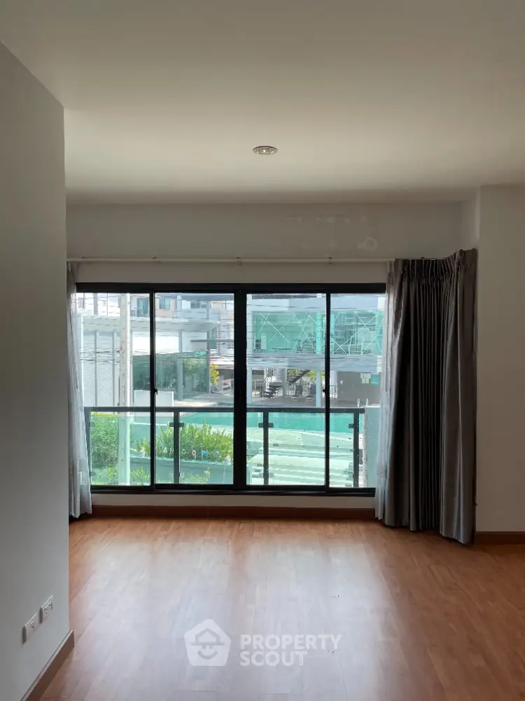 Spacious living room with large windows and wooden flooring, offering a bright and airy ambiance.