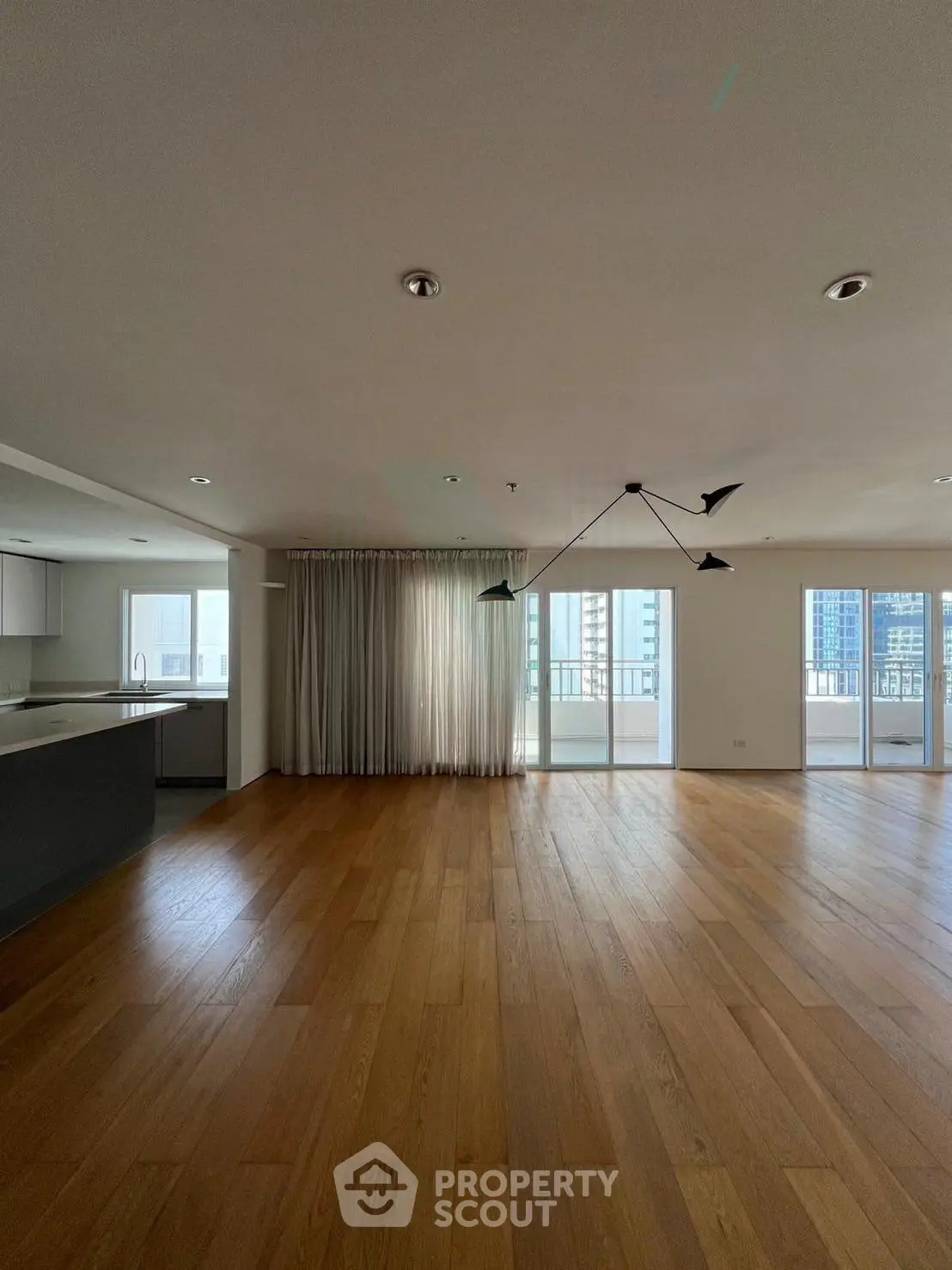 Spacious modern living room with wooden floors and large windows in a luxury apartment.