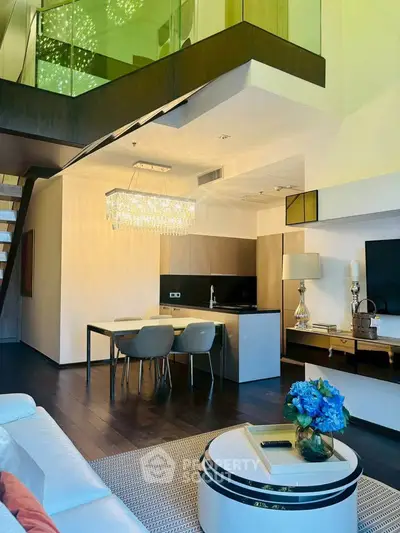 Luxurious modern living room with mezzanine, elegant chandelier, and stylish open kitchen layout.