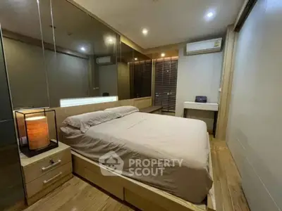 Modern bedroom with wooden flooring, mirrored wall, and ambient lighting
