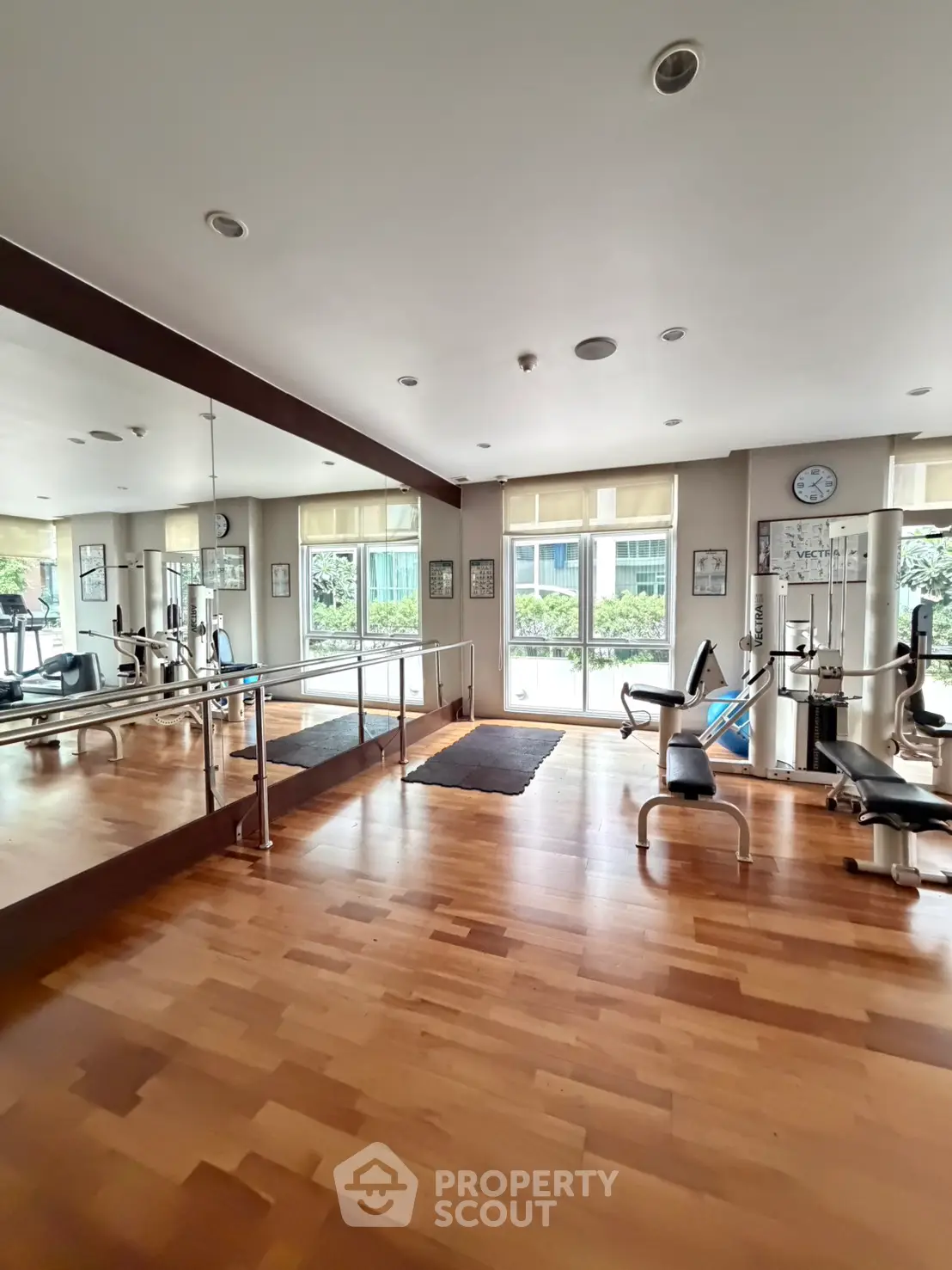 Spacious gym with modern equipment and large mirrors in a residential building.