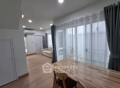 Spacious modern living room with wooden flooring and large windows for natural light.