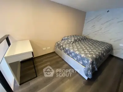 Modern bedroom with stylish decor and wooden flooring, featuring a cozy bed and sleek desk.