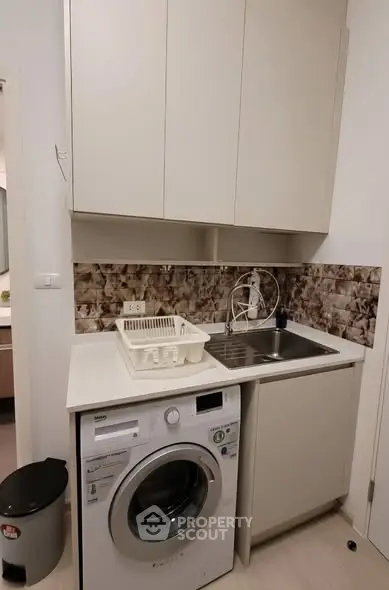 Modern laundry area with washing machine and sink in compact space