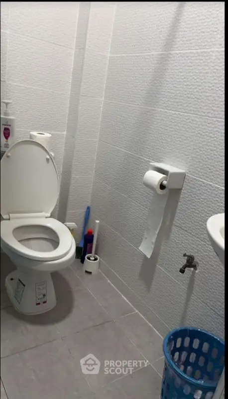 Modern bathroom with white tiles and essential amenities.