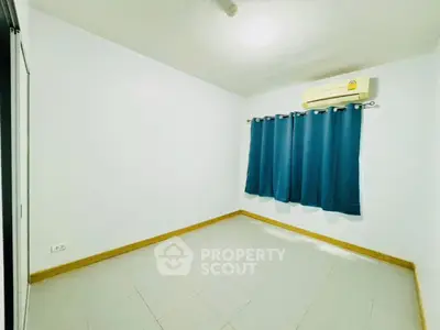 Spacious empty room with air conditioning and blue curtains, ideal for customization.