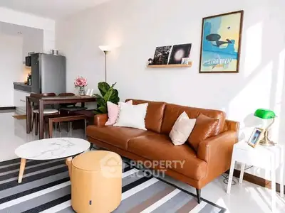 Stylish living room with leather sofa, modern decor, and open kitchen layout.