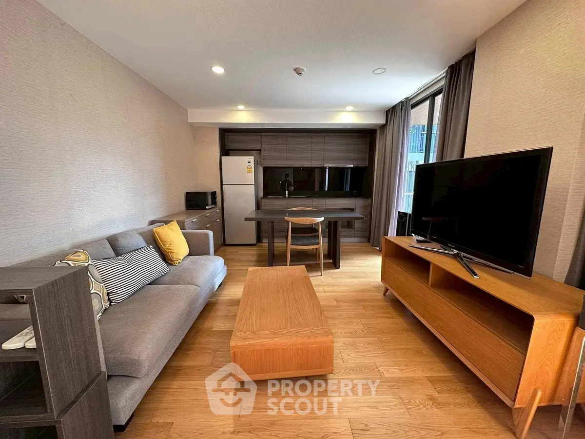 Modern living room with stylish furniture and open layout, featuring a cozy sofa and large TV.