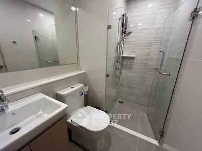 Modern bathroom with glass shower and sleek fixtures in a contemporary apartment.