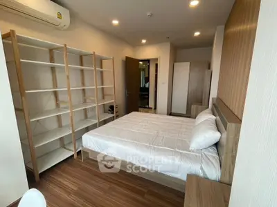 Modern bedroom with wooden flooring and open shelving in a stylish apartment.