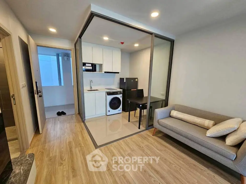 Modern apartment with open kitchen and cozy living area, featuring sleek design and natural light.