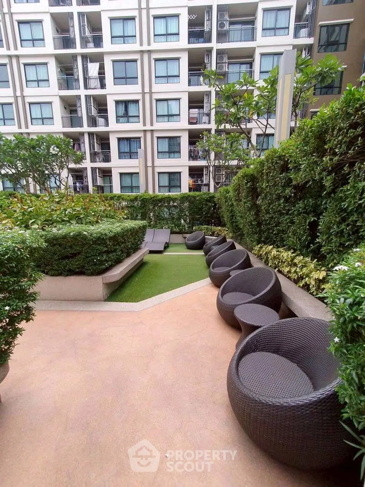 Modern apartment building with lush garden and stylish outdoor seating area.