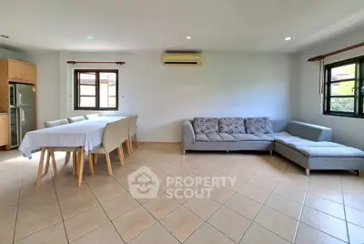 Spacious living room with modern furniture and dining area, featuring large windows and tiled flooring.