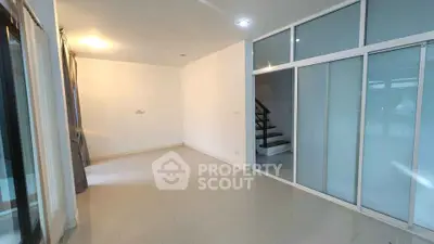 Spacious modern living room with sliding glass doors and staircase, perfect for contemporary living.