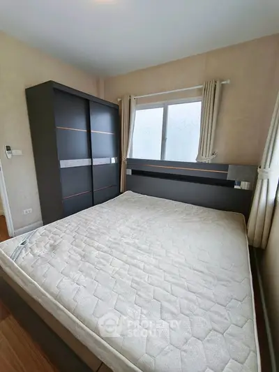 Modern bedroom with sleek wardrobe and large window for natural light.