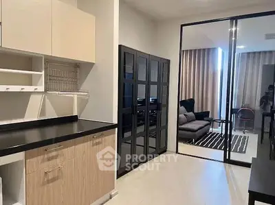 Modern kitchen with sleek cabinetry and open layout leading to a stylish living room.