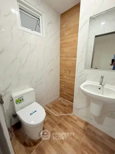 Modern bathroom with sleek design, featuring a toilet, sink, and stylish tile flooring.