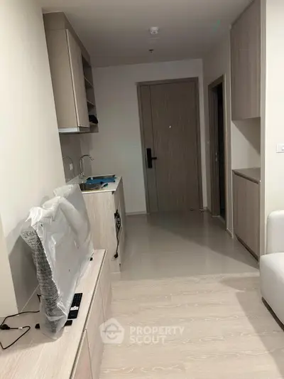Modern apartment interior with sleek kitchen and cozy living area, featuring contemporary design and efficient layout.