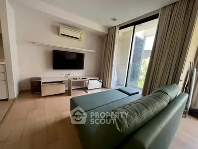 Modern living room with sleek furniture and large window offering natural light.